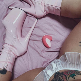 Light pink sky high stilettos with legs crossed around pink Unbound Puff Suction Toy on light pink sheets and lace white lingerie