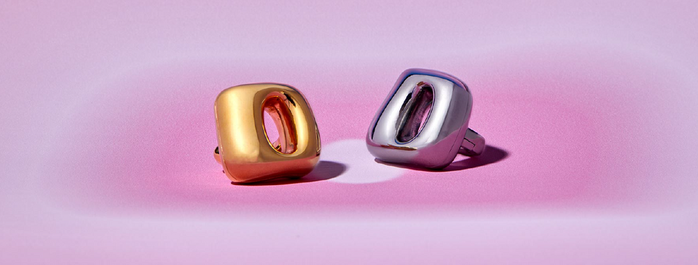 unbound flick vibrating ring in gold and silver on pink backdrop