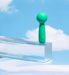 Green handheld device on a clear platform with a blue sky background