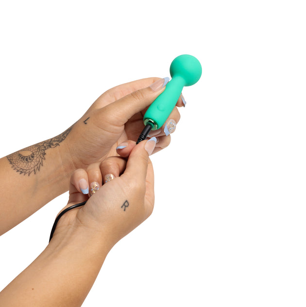 Hand holding a turquoise hair tie against a white background
