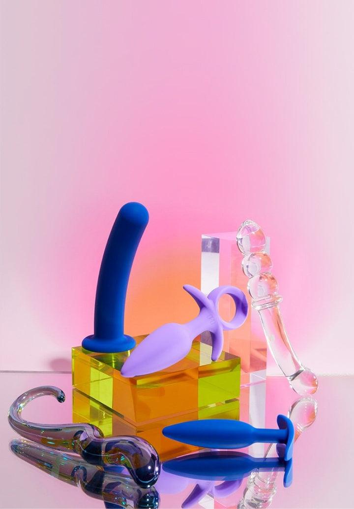 Product display image with Unbound vibrators, dildos,  and plugs on a light pink background