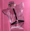clear torso body mannequin wearing black and gold harness on a pink background