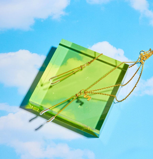 Close-up of clamps on a bright blue background with clouds and a clear lime green cube 